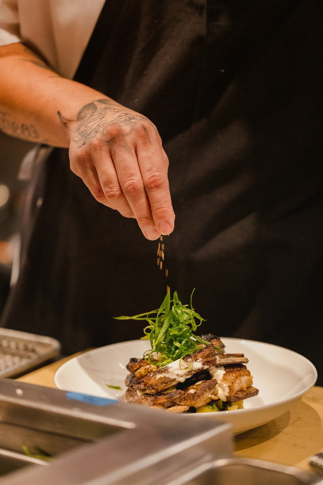 Un cocinero termina un plato en el pase de la cocina