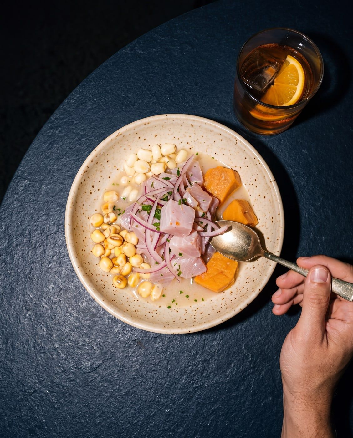 Ceviche de corvina con leche de tigre, visto desde arriba sobre pizarra oscura