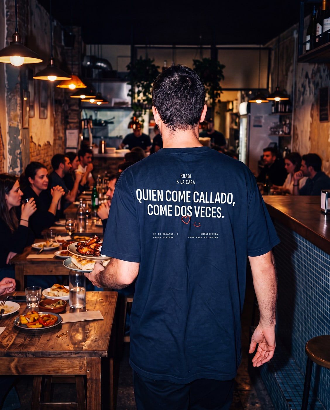 Camarera de espaldas con el lema de Krabi en la camiseta, en la sala